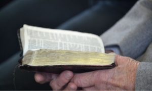 A elderly hand holding a Bible