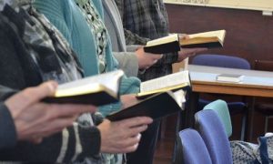 A row of people holding hymnbooks